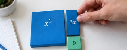 Hand arranging blue algebra tiles on a desk